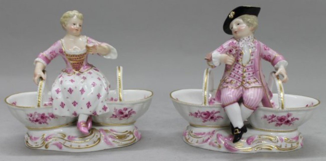 A Pair of Meissen Porcelain Figural Sweetmeat Dishes: A Pair of Meissen Porcelain Figural Sweetmeat Dishes, depicting a boy and girl in 18th century attire resting atop the segmented bowls, having crossed swords mark in blue underglaze with further impre