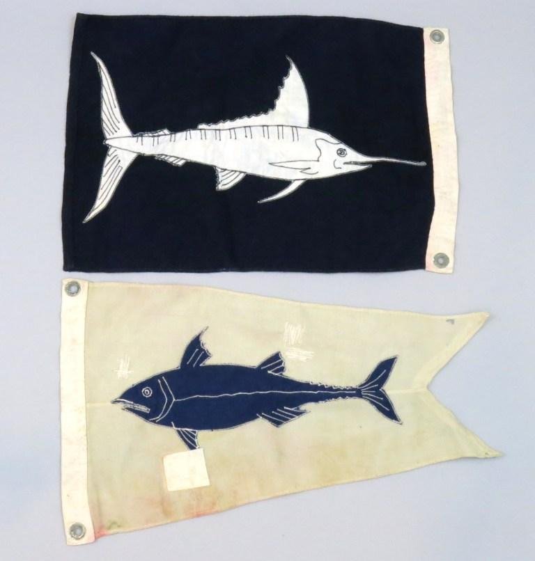 Marlin and Tuna Catch Flags: The marlin flag measures 17 1/2" x 11 1/2" and is in Very Good plus condition and the tuna flag measures 18 1/2" x 10 1/2" and is in good condition with what appears to be an old cloth tape repair.