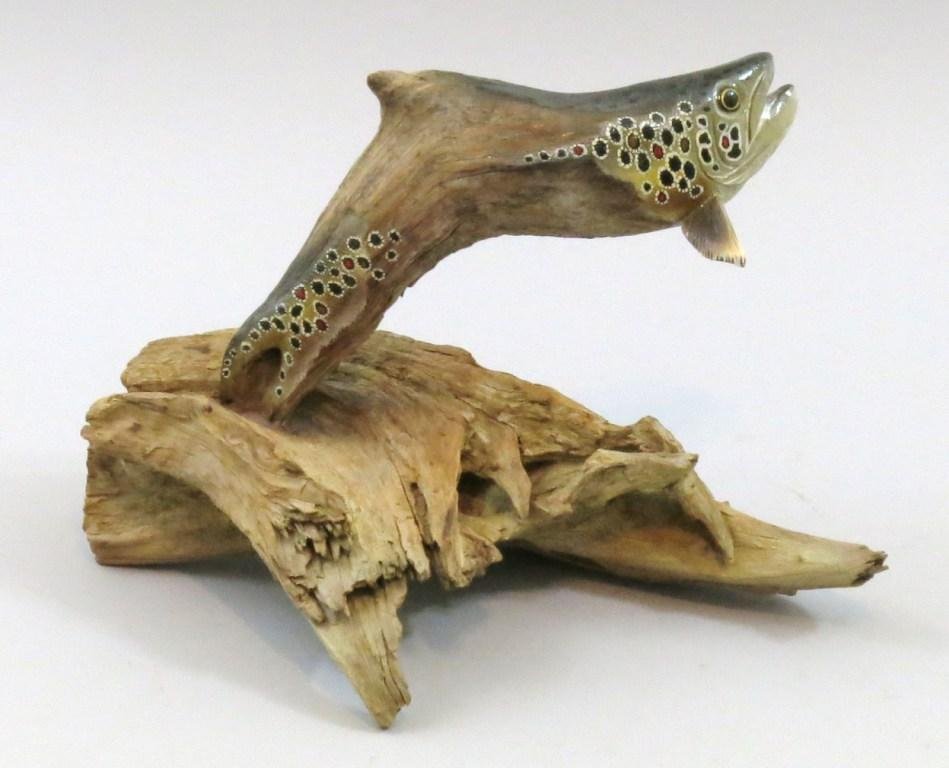 Driftwood Carving of a Brown Trout by Jim Wiley: Measuring 12 " x 8" of a stylized brown trout on a driftwood base. Signed by the carver with his code "1217", carved in 2012 and the seventeenth carving of that year. This contemporary carver's style