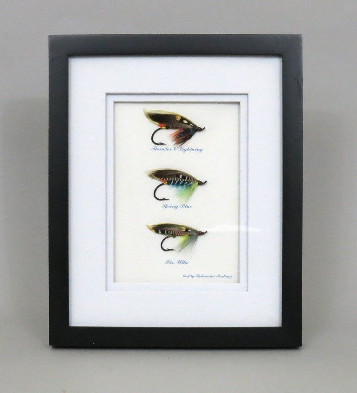 Three Salmon Flies by Belarmino Martinez: The patterns are "Thunder & Lightning", "Spring Blue", and "Rio Ulla". First two are tied on 4/0 and the last on 2/0 All tied using up turn eye hooks. Housed in a 9" x 11" double matted frame with the