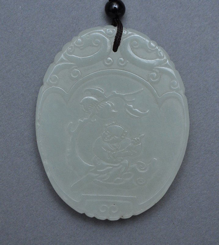 A Chinese Jade Oval Plaque: A Chinese Jade Oval Plaque depicting a young lad paddling below peaches on one side and the reverse showing fruits and flowers. Height: 5.2cm, Weight: 27.0g. 玉牌