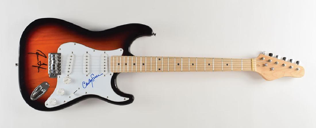 Carly Simon and James Taylor Signed Guitar: Stratocaster-style electric guitar with a sunburst finish, nicely signed on the pickguard in blue felt tip by Carly Simon, and boldly signed on the body in black felt tip by James Taylor. In fine cond
