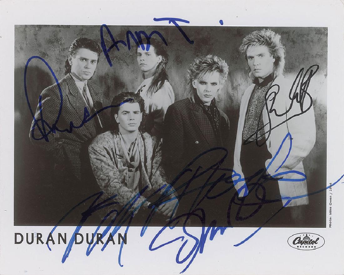 Duran Duran Signed Photograph: Glossy 10 x 8 Capitol Records publicity photo of Duran Duran from 1984, signed in felt tip by Simon Le Bon, Nick Rhodes, Roger Taylor, John Taylor, and Andy Taylor. In fine condition.