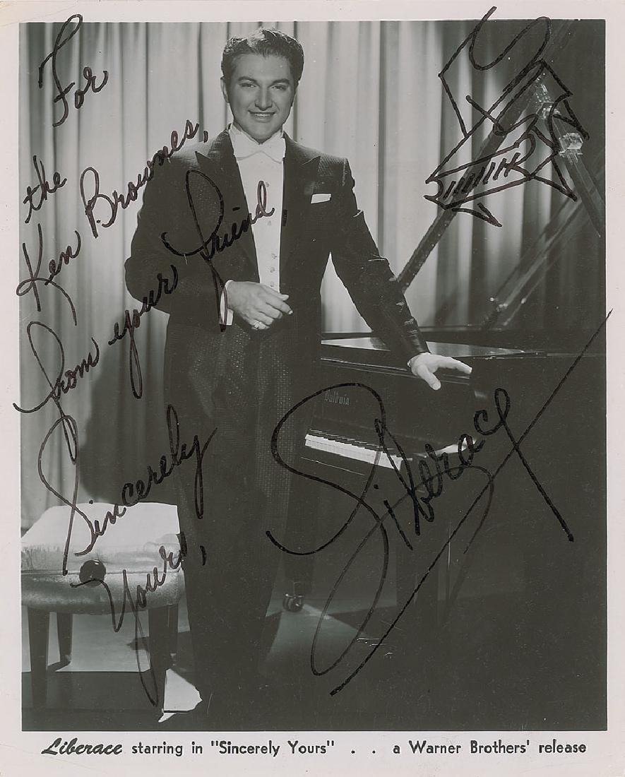 Liberace: Vintage glossy 8 x 10 Warner Bros. publicity photo of Liberace posing beside his piano, signed and inscribed in black felt tip, "For the Ken Brownes, from your friend, Sincerely yours, Liberace.” He
