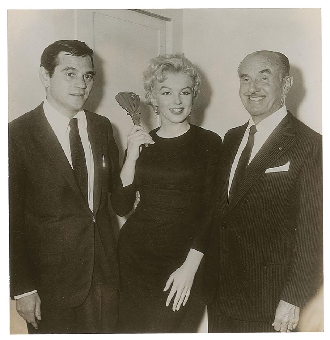 Marilyn Monroe and Jack Warner Original Vintage: Original vintage glossy 7.5 x 7.75 silver gelatin photograph of Marilyn Monroe with photographer Milton Greene and studio head Jack L. Warner, showing Monroe holding up a large Warner Bros. key presen