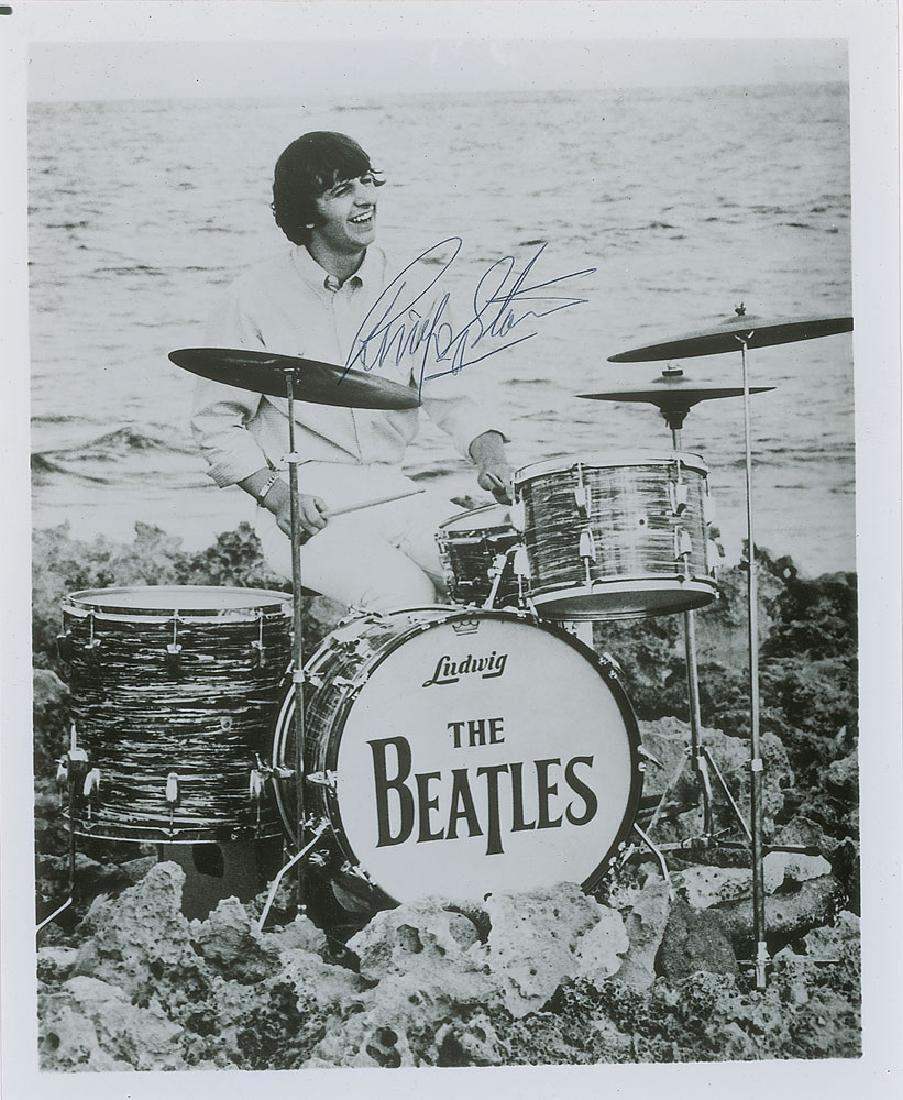 Beatles: Ringo Starr: Glossy 8 x 9.75 full-length photo of Ringo Starr playing his drums on a rocky shoreline, signed in black ballpoint. In fine condition.