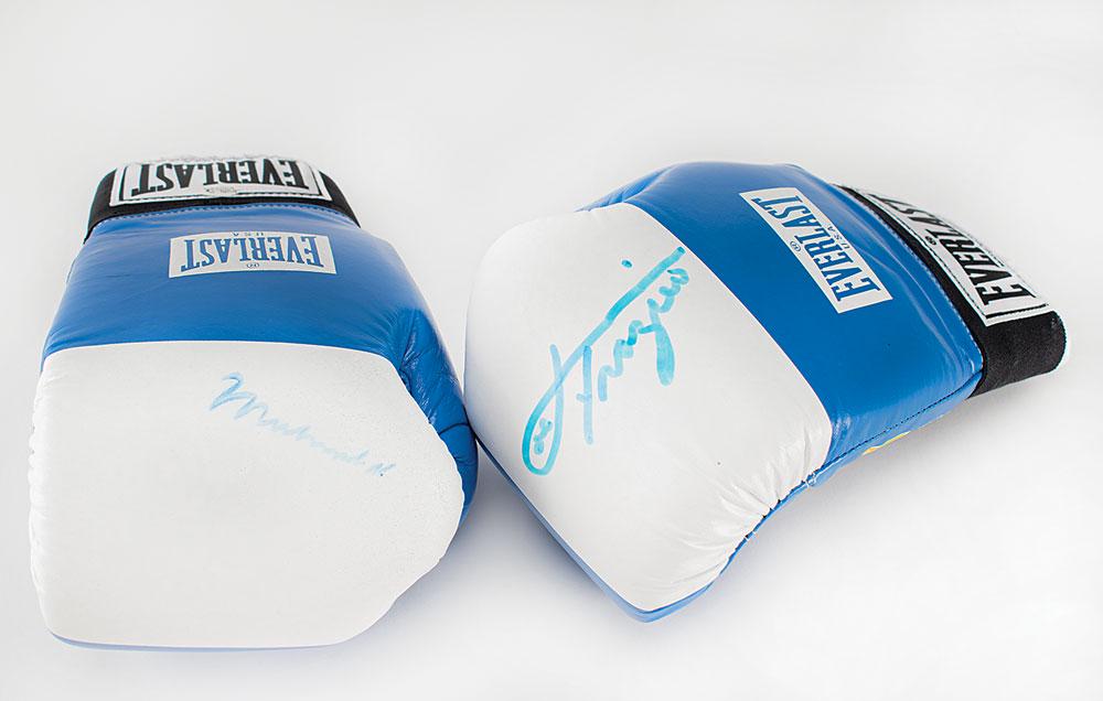 Muhammad Ali and Joe Frazier: Pair of blue-and-white Everlast boxing gloves, with the right glove signed in blue felt tip by Muhammad Ali, and the left glove signed in blue felt tip by Joe Frazier. In overall fine condition, with