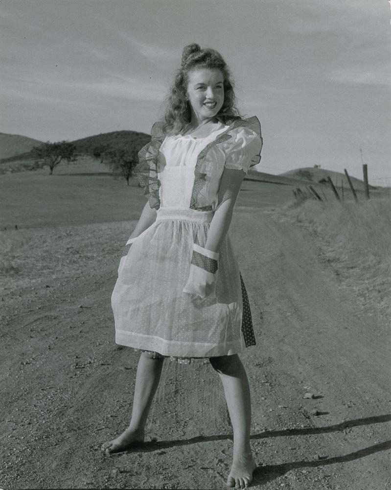 Marilyn Monroe: Sharp original vintage glossy 10.75 x 13.5 silver gelatin photograph of the young Marilyn Monroe outdoors and barefoot, taken by Andre de Dienes in 1945. Reverse bears multiple Andre de Dienes credit