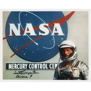 Scott Carpenter Signed Photograph: Color satin-finish 10 x 8 photo of Carpenter wearing his Mercury space suit and posing in front of the NASA 'meatball' logo at the Mercury Control Center, signed in black felt tip, "Scott Carpenter,