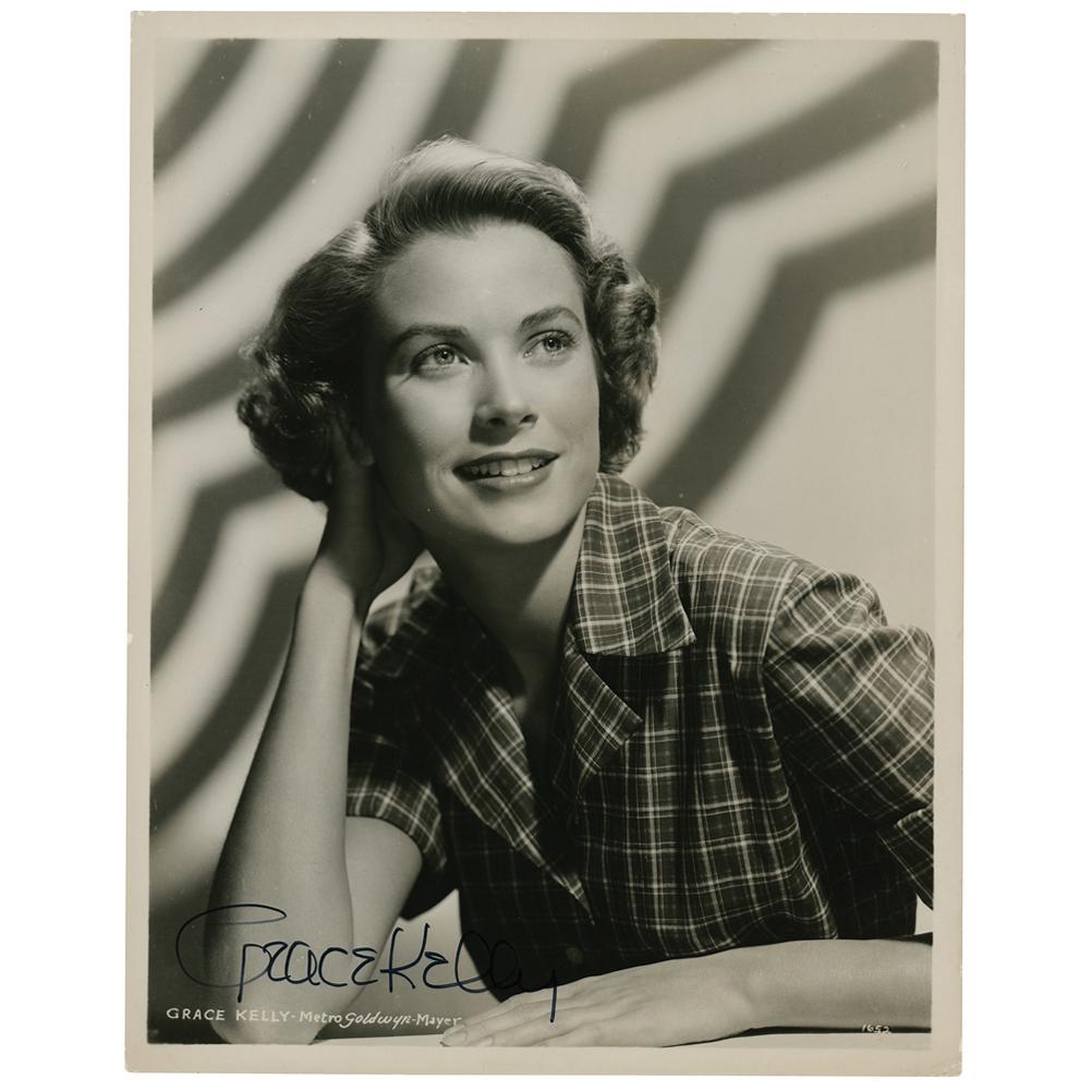 Grace Kelly Signed Photograph: Gorgeous glossy 8 x 10 MGM publicity photo of Grace Kelly in a plaid top for the 1953 John Ford film Mogambo, signed in black felt tip. In fine condition, with scattered light creasing. Co-starring al