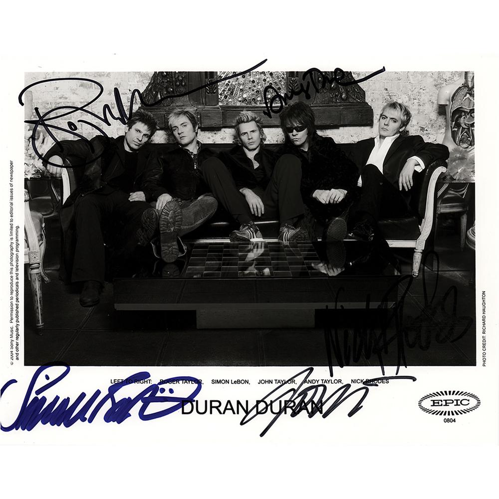 Duran Duran Signed Photograph: Satin-finish 10 x 8 Epic Records publicity photo of Duran Duran lounging together on a couch, signed in purple felt tip by Simon Le Bon, and in black felt tip by Nick Rhodes, John Taylor, Andy Taylor,