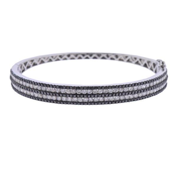 14K Gold 4.26ctw Black White Diamond Bangle Bracelet: METAL: 14k Gold. GEMSTONES: White and black diamonds total approx. 4.26ctw. MEASUREMENTS: Bracelet will fit 7.50" wrist (inner diameter - 61mm x 54mm wide) and is 7.5mm at widest point. MARKED: M