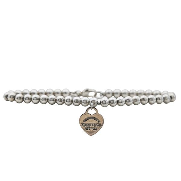 Tiffany & Co. Sterling Silver Ball Bracelet with Metal Return to Tiffany Heart Tag: Bracelet length 6 inches. Signed Tiffany & Co. AG925. Heart Tag signed T&Co., Metal, Please Return to Tiffany & Co. New York. 5.2 grams. Comes with pouch.