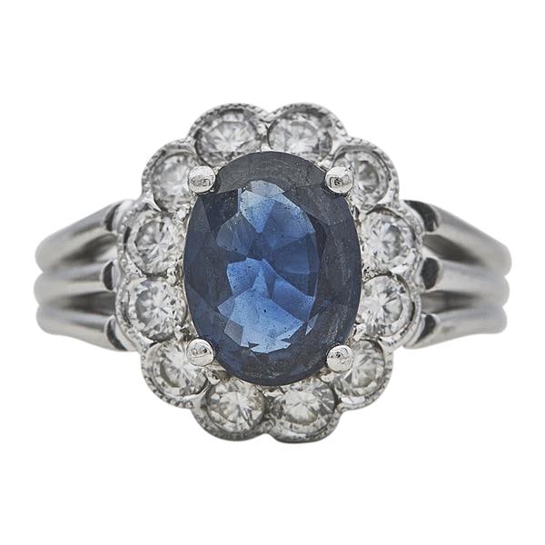 18k White Gold Oval-Shaped Sapphire and Diamond Halo Ring: Diamonds weighing approx. 0.60 ctw. Ring size 5 1/2. Stamped 750, CTF. 5.8 grams. Gemstones have not been graded for color and clarity, and tested for clarity and color enhancement, unless stated othe