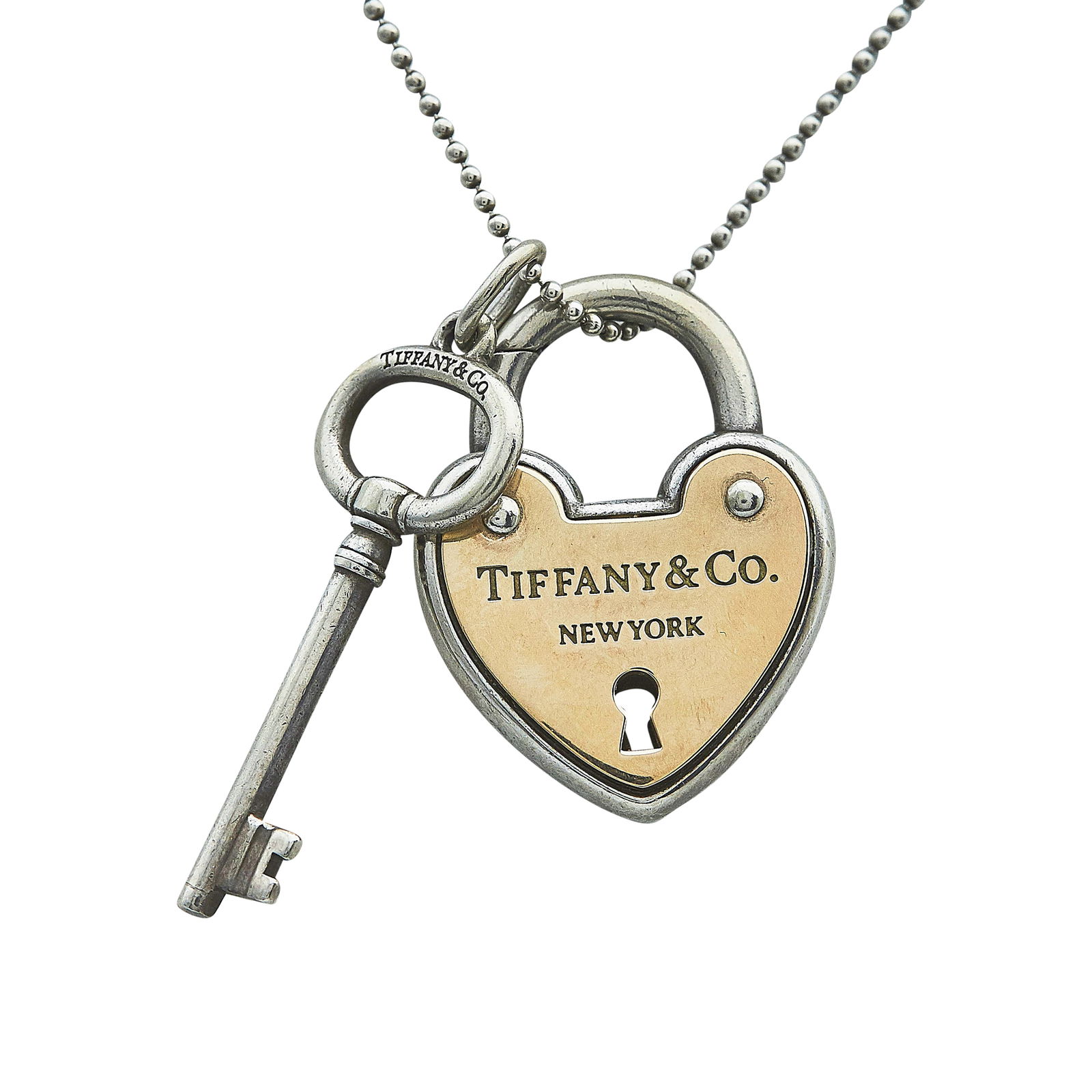 Tiffany & Co. Sterling Silver and 18K Yellow Gold Key and Lock Pendant Necklace: BRAND: Tiffany & Co.; METAL: Silver, 18K Yellow Gold; STAMPED: Lock Pendant marked: © T & Co., 925, 750; Key Pendant marked: © Tiffany & Co., 925; Chain marked: © Tiffany & Co., 925; CONDITION: