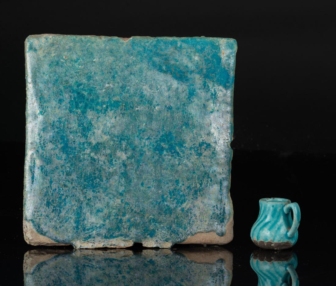 Arte Islamica A turquoise glazed pottery tile and: Islamic Art A turquoise glazed pottery tile and small pitcher Ira, Kashan, 12th century . . Cm 21,50.