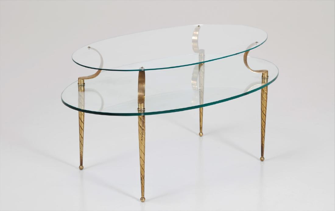 MANIFATTURA ITALIANA Oval coffee table.: ITALIAN MANUFACTURE Oval coffee table. Brass and glass. Cm 94,00 x 57,00 x 49,00. Brass legs, double glass top.