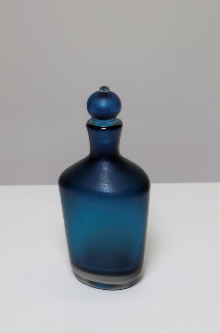 PAOLO VENINI Bottle with cap.: Bottle with cap. Murano glass. Cm 13,00 x 28,50 x 13,00. Heavy blue intense glass, overlapping colors, finished by light horizontal incisions on the whole surface. The object has an oval section body