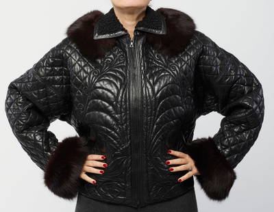 GIANNI VERSACE Black quilted bomber jacket with hood and fur details.: VERSACE GIANNI (1946 - 1997) Black quilted bomber jacket with hood and fur details. 1990. Leather. . Padded bomber jacket in quilted black leather and wool, removable black fur collar. Internal label