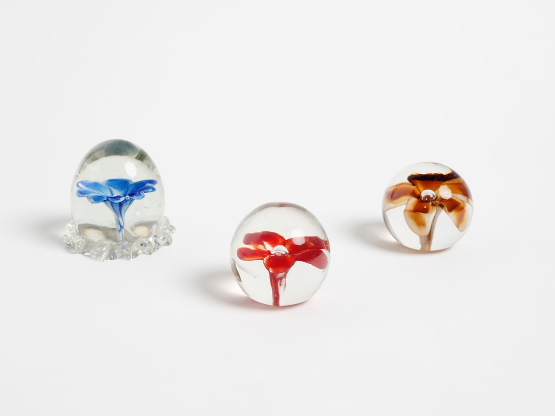 VENINI Three presse papier, Murano.: VENINI Three presse papier, Murano. Crystal glass with the inclusion of a floral element in blue, amber and red incamiciato glass and an air bubble included.. . 1950s.Signed under the bases (two with