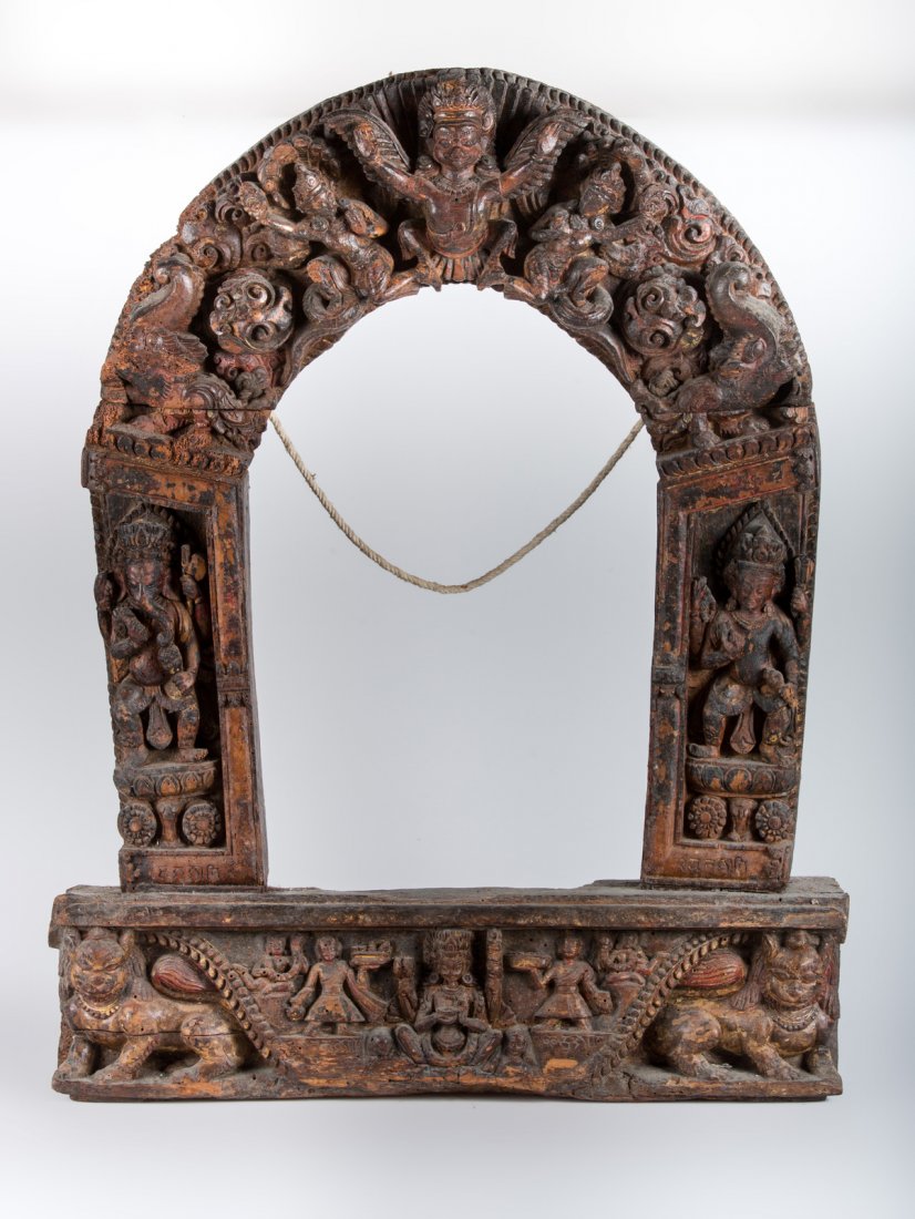 Arte Himalayana A wooden carved turana Nepal, 18th: A wooden carved turana Nepal, 18th century . . Cm 61,50 x 76,50. Turana, in all likelihood originally from a small temple, portraying in the center of the upper arch the winged god Garuda, with two na