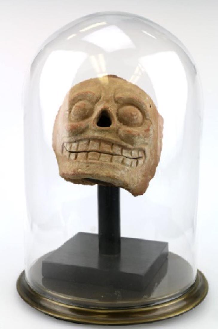 PRE-COLUMBIAN MAYAN MOLDED SKULL APPLIQUE: PRE-COLUMBIAN MAYAN MOLDED SKILL APLLIQUE, CA 500-800 AD, 6 3/4" H, MOLDED TERRACOTTA SKELETAL FACE HAVING WIDE, TOOTHY GRIN, HOLLOW NOSE, AND BULGING EYES WITHIN SUNKEN ORBSITS. TRACES OF WHITE SLIP 