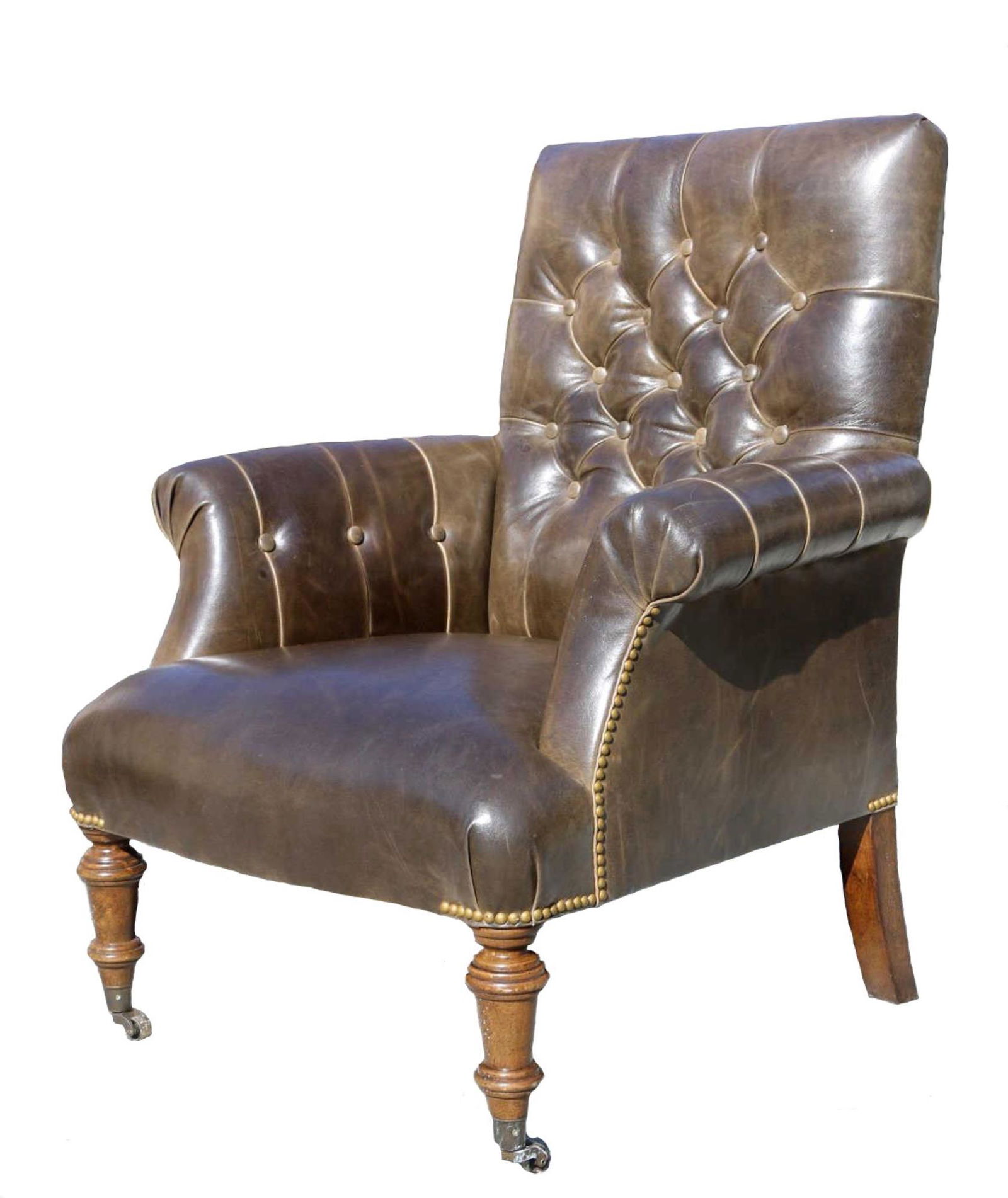 ENGLISH ANTIQUE NAIL TRIMMED LEATHER ARM CHAIR: ENGLISH ANTIQUE NAIL TRIMMED LEATHER ARM CHAIR TUFTED WITH A TURNED LEG AND BRASS CASTER FROM THE LAKE TOXAWAY MOUNTAIN ESTATE Condition GOOD H 41 W 30 D 24 in