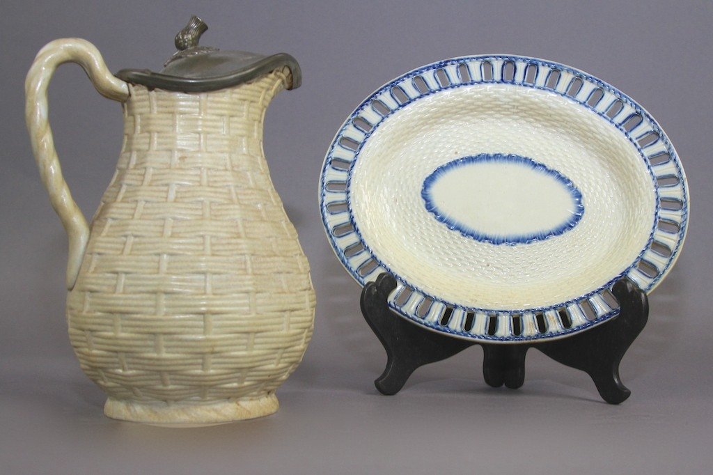TWO PIECES OF CREAMWARE POTTERY: A basket weave pitcher with pewter lid, and oval under plate. Pitcher: 9.5"H X 5.5"D X 7"W . Plate: 8"H X 10"W.
