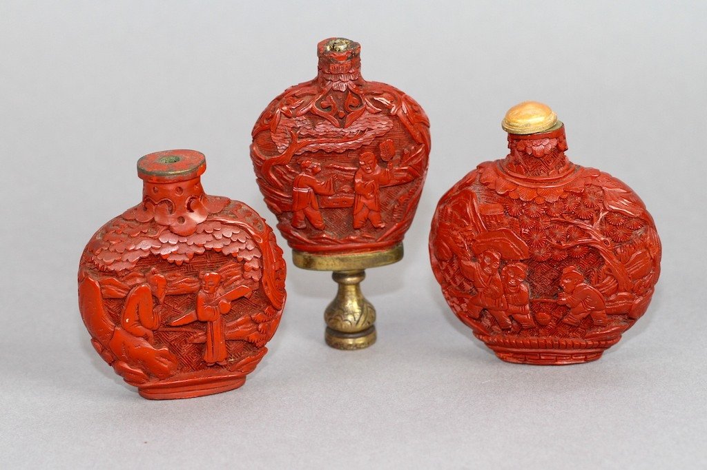 THREE CARVED CHINESE CINNABAR SNUFF BOTTLES:: Tallest measures 3.5"H