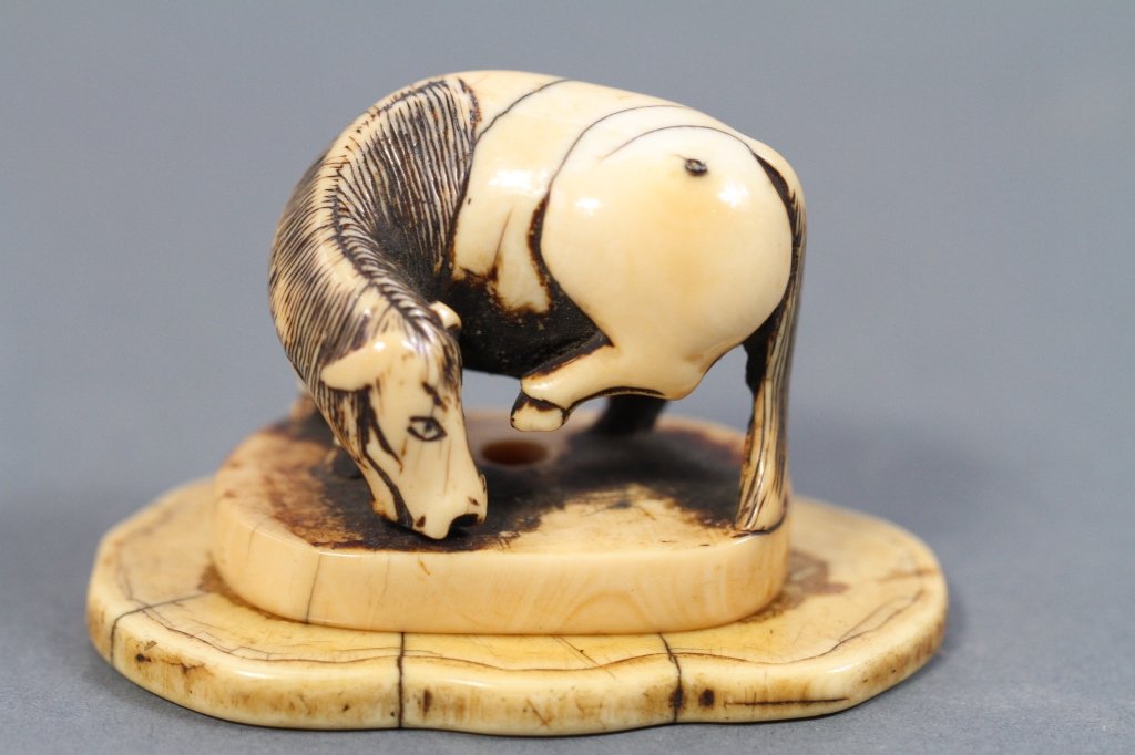 CHINESE / JAPANESE NETSUKE ON IVORY PLINTH: Horse: 1.5"H X 1.75"W X 1.25"D_x000D_ With plinth: 2"H X 2.75"W X 1.5"D