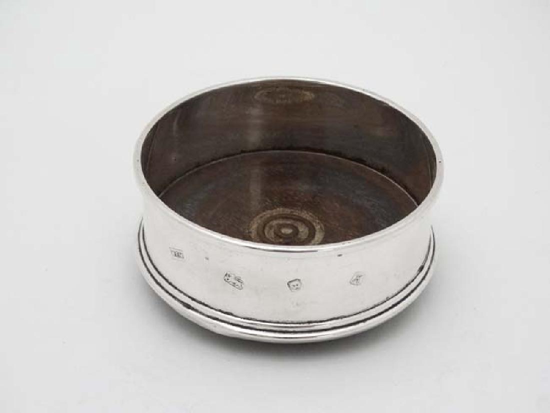 A silver coaster with turned wooden base London 1984: A silver coaster with turned wooden base London 1984 maker WEV 3 3/4'' diameter