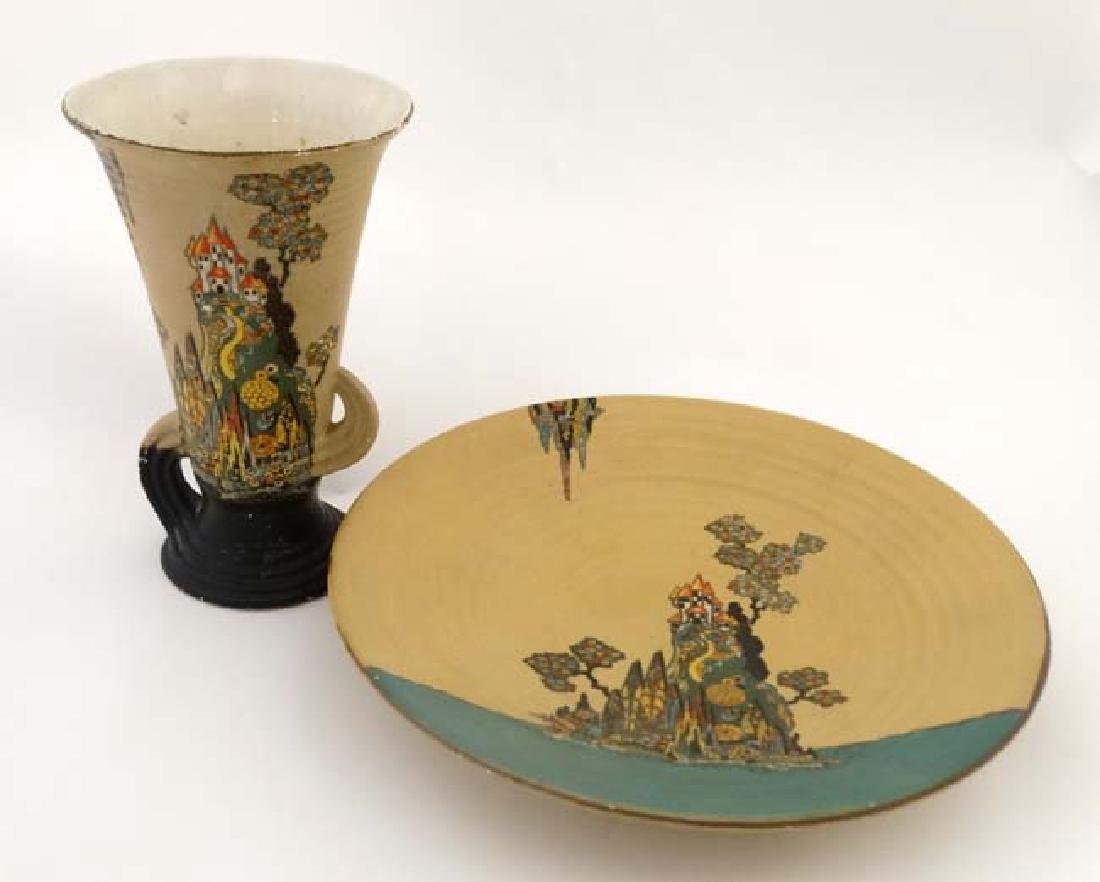 An Art Deco twin handled vase , decorated in polychrome: An Art Deco twin handled vase , decorated in polychrome with buildings upon a stylised mountain on a buff ground , together with matching plate, bears registered design number to base. The vase 8 1/2'