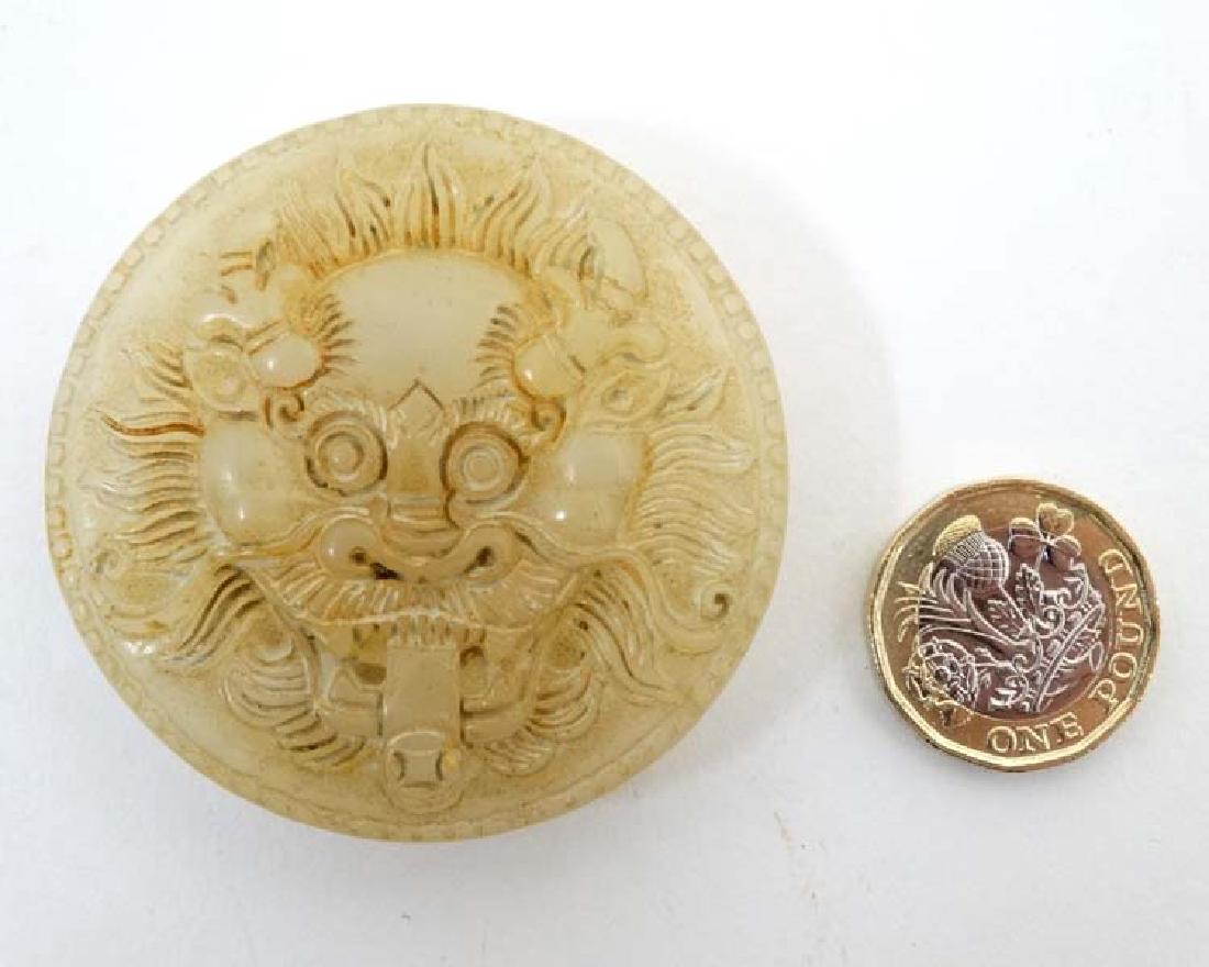 A carved mutton fat jade belt buckle formed as the head: A carved mutton fat jade belt buckle formed as the head of a dragon 2 1/8'' diameter
