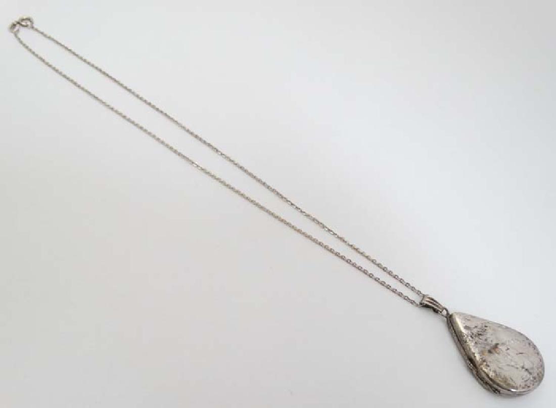 A silver locket of drop form with engraved decoration 1: A silver locket of drop form with engraved decoration 1 ½'' long on a silver chain 16'' long