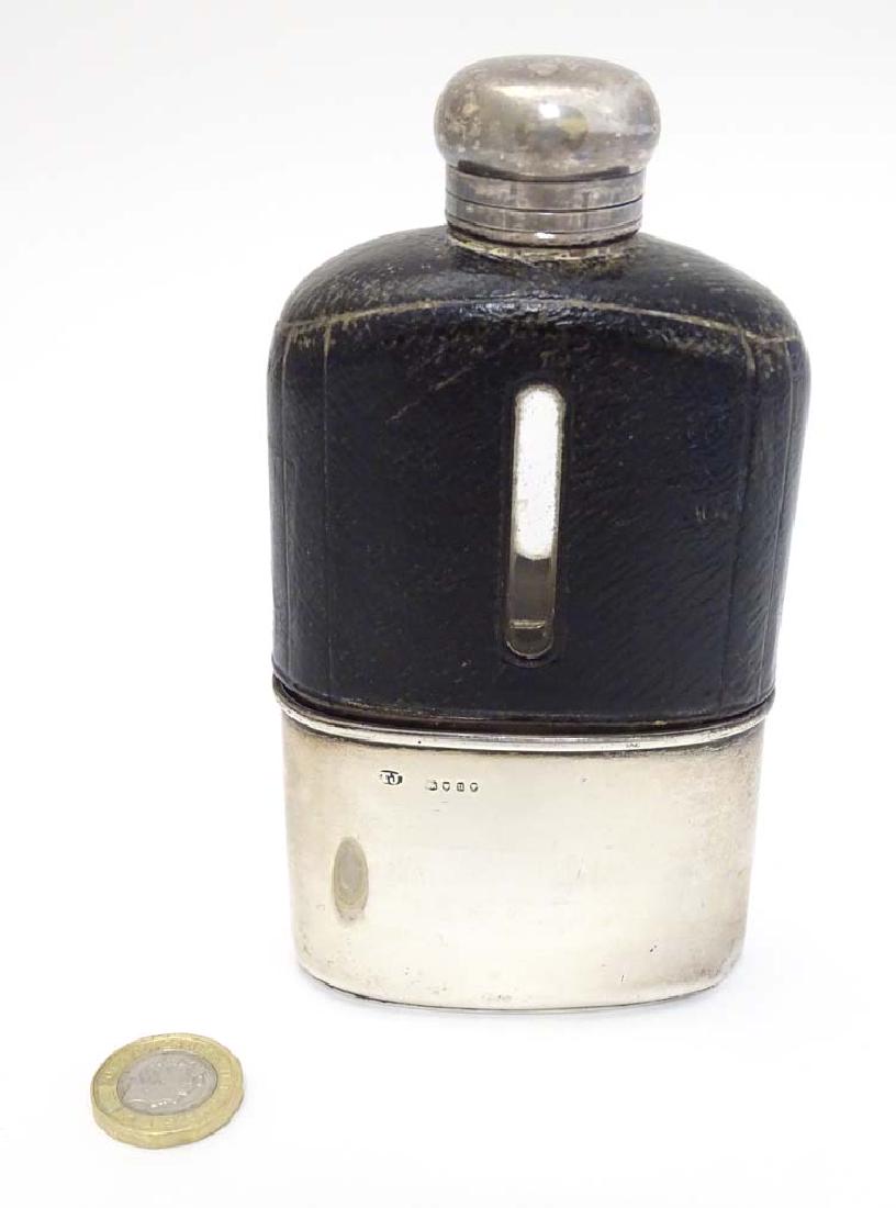 A glass hip flask with half leather covering and silver: A glass hip flask with half leather covering and silver beaker to lower half, hallmarked London 1875 maker Thomas Johnson. 5 1/2'' high