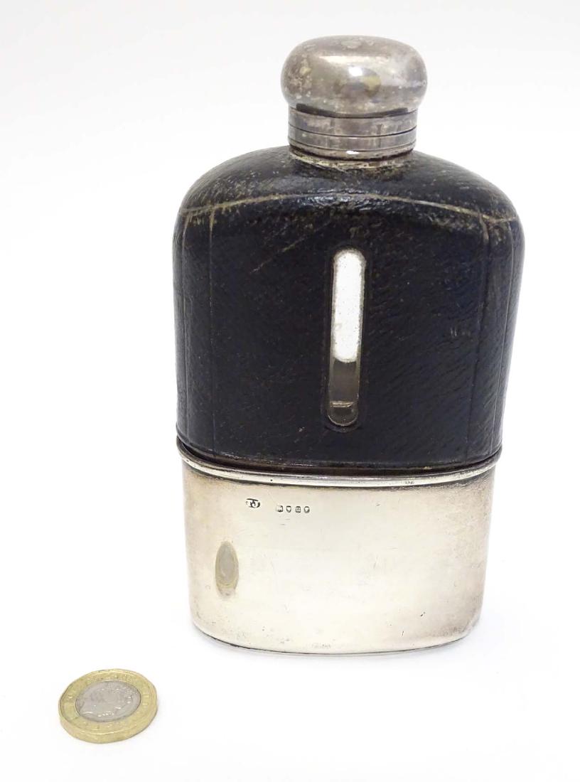 A glass hip flask with half leather covering and silver: A glass hip flask with half leather covering and silver beaker to lower half, hallmarked London 1875 maker Thomas Johnson. 5 1/2'' high