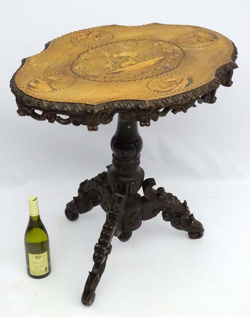 A 19thC black forest tilt top table with marquetry: A 19thC black forest tilt top table with marquetry inlaid images of chamois deer, parquetry decoration and impressive hand carved oval rim, having a tripod base with intricately carved decoration thro