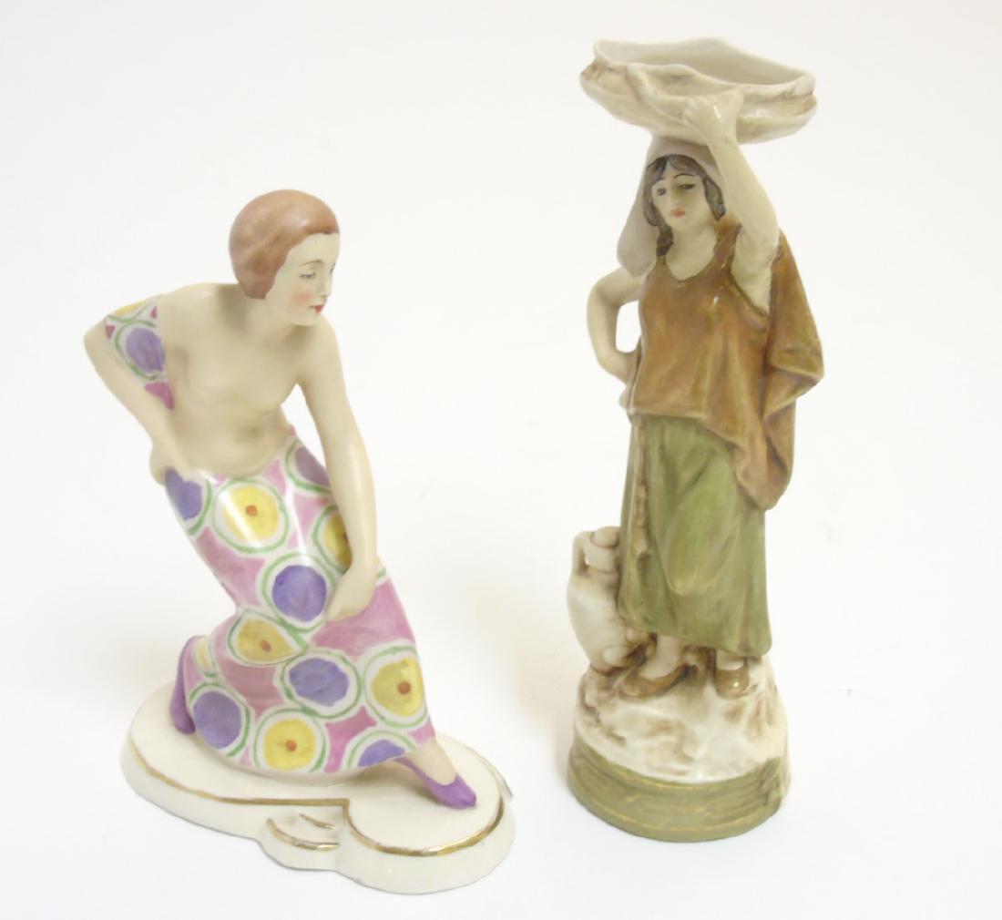 Two Royal Dux Bohemia figures, comprising an Art Deco: Two Royal Dux Bohemia figures, comprising an Art Deco figure of a semi nude female figure dancing and another of a girl carrying a basket on her head, impressed makers E triangle to base, tallest 7 1/