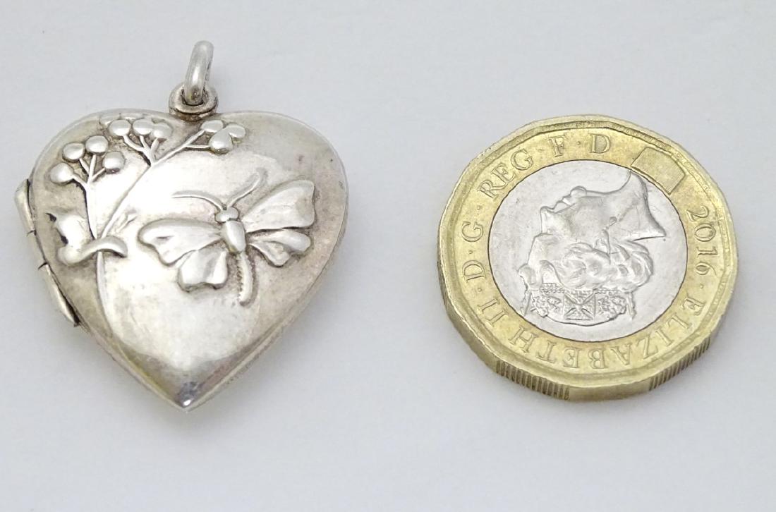A silver heart shaped locket with foliate and butterfly: A silver heart shaped locket with foliate and butterfly decoration. Approx 1'' long