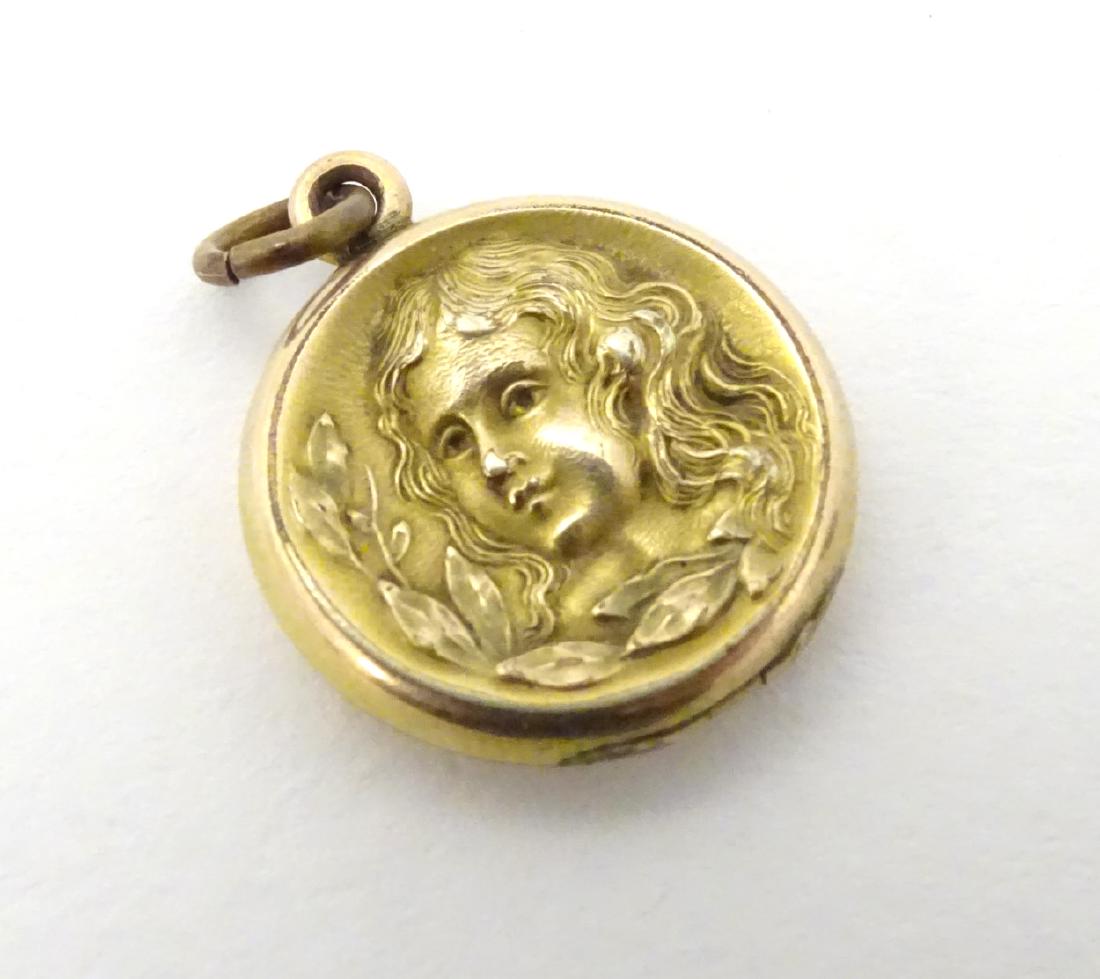 A gilt metal pendant locket with decoration to one side: A gilt metal pendant locket with decoration to one side depicting the head of a young girl ¾'' wide