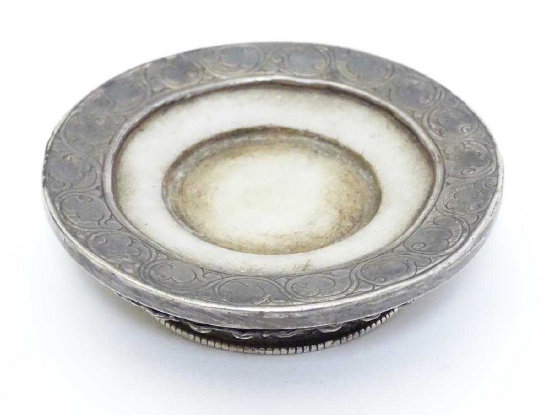 An Oriental / Tibetan mutton fat Jade saucer/stand with: An Oriental / Tibetan mutton fat Jade saucer/stand with white metal mounts having engraved mythical beast decoration. 3 1/2'' diameter