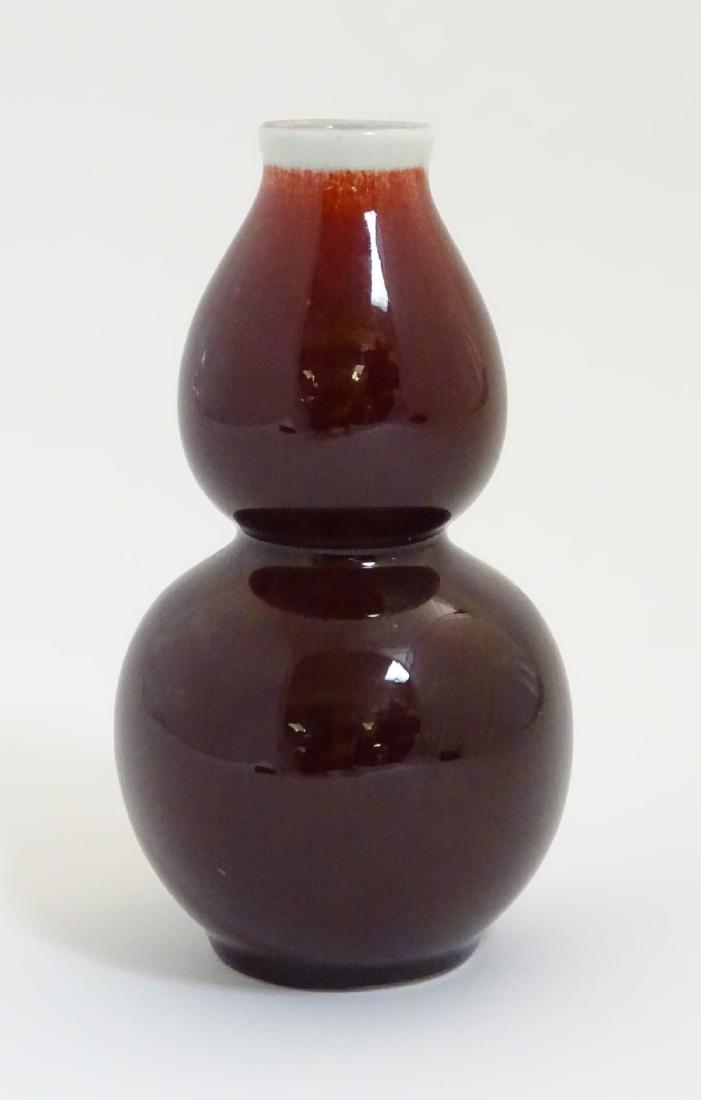 A Chinese sang-de-boeuf double gourd, high fired: A Chinese sang-de-boeuf double gourd, high fired porcelain vase. Indistinct Chinese marking to base. Height: approx. 6 1/2''