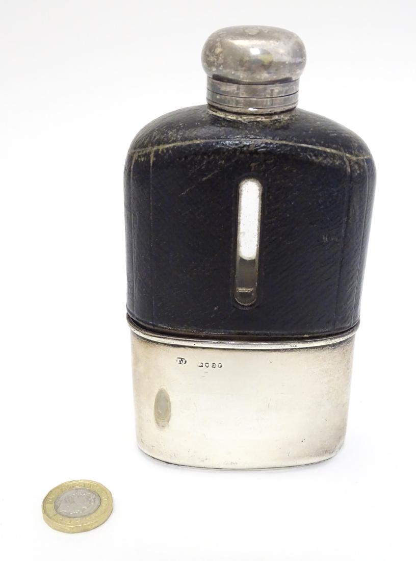 A glass hip flask with half leather covering and silver: A glass hip flask with half leather covering and silver beaker to lower half, hallmarked London 1875 maker Thomas Johnson. 5 1/2'' high