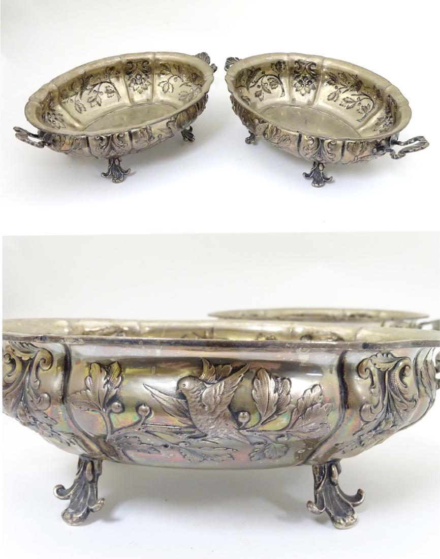 A pair of late 19thC / early 20thC Austro-Hungarian: A pair of late 19thC / early 20thC Austro-Hungarian silver (.800) serving dishes having twin handles and with floral foliate and bird decoration. Marked under RS, HD and stamped Schwarz & Steiner. 11'