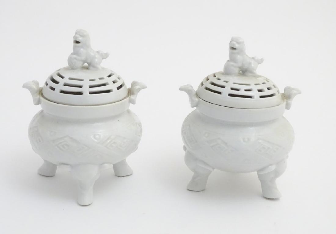 A pair of three footed, twin handled oriental ceramic: A pair of three footed, twin handled oriental ceramic censers both with banded geometric decoration to the body and pierced decoration to the lid, topped with a foo dog. Approx. 7 1/4'' high