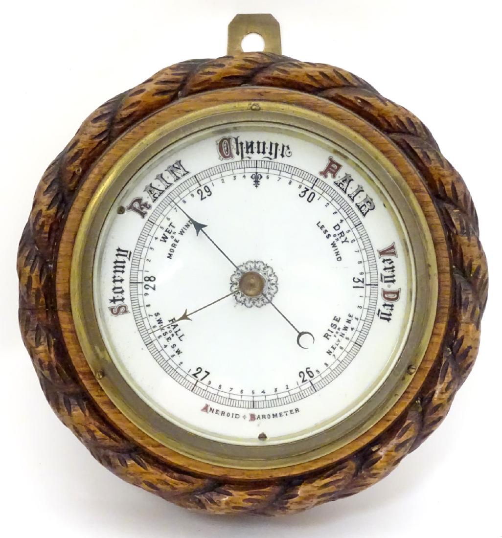 Aneroid Barometer: a circular oak cased barometer: Aneroid Barometer: a circular oak cased barometer having rope twist decoration and white dial, 7 1/4'' diameter.