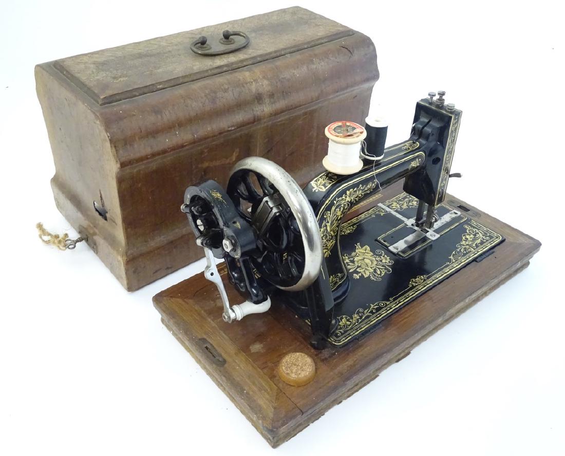 A Tryer sewing machine decorated with a gilt floral: A Tryer sewing machine decorated with a gilt floral design, mounted on a wooden base with a side on case. Manufactured in Germany.