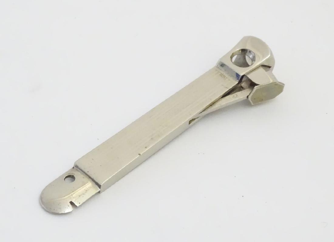 A 20thC stainless steel cigar cutter, the sprung blade: A 20thC stainless steel cigar cutter, the sprung blade section stamped with makers? antler within shield mark. The body with engine turned decoration. 5 7/8'' long