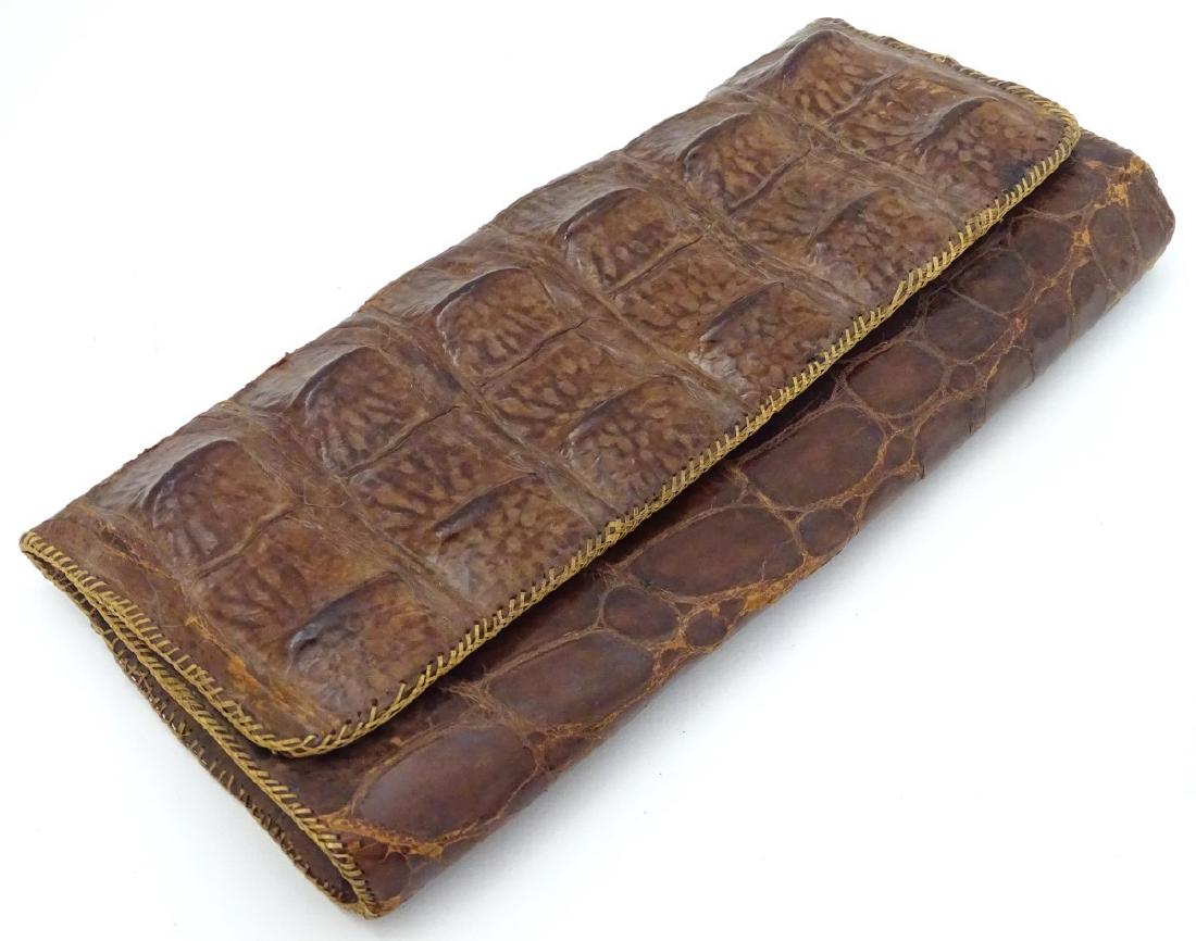 An early to mid 20thC crocodile clutch bag with: An early to mid 20thC crocodile clutch bag with compartments within. Bear gold stamp inside 'Genuine Crocodile, Made in Indonesia'. 11'' wide x 5 1/4'' high.