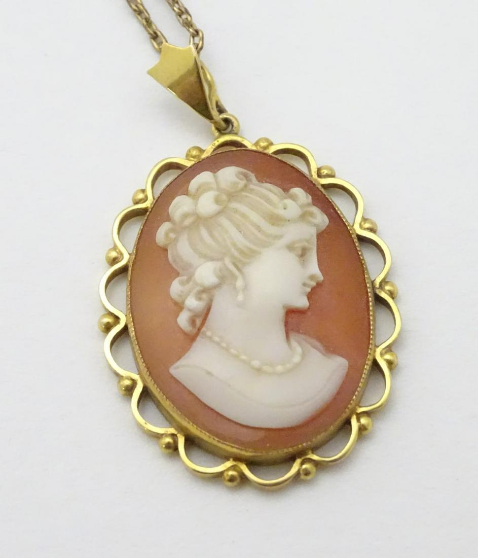 A 9ct gold cameo pendant on a gilt metal chain. The: A 9ct gold cameo pendant on a gilt metal chain. The pendant 1 1/2'' long